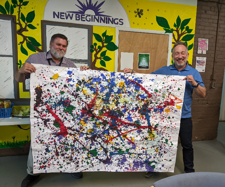  At the Mental Health Association in Chautauqua County’s first monthly Recovery Luncheon since COVID, Program Director Michael Nordin (left) and Executive Director Steven Cobb display artwork from a recent Fun Friday. The painting will be framed and hung at the facility.