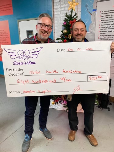 Mental Health Association Executive Director Steven Cobb and Jamie Billquist hold a check from Rosie’s Run, the annual 5K run/walk in memory of Rosemary “Rosie” Billquist. The donation is for supplies at the new warming center in Jamestown’s Gateway Center.