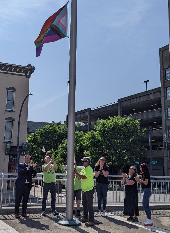 Jamestown Mayor Eddie Sundquist (left) applauds as the Progress Pride Flag is raised on City Hall’s Tracy Plaza last Friday in conjunction with the Jamestown Pride Festival events this weekend.